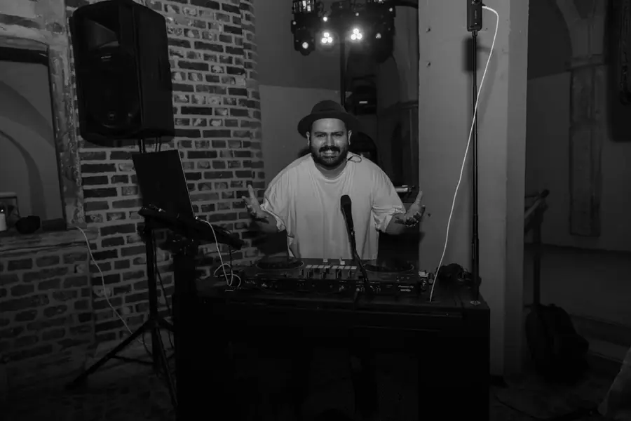 DJ SAM am Pult vor rustikaler Backsteinwand &ndash; Schwarzwei&szlig;