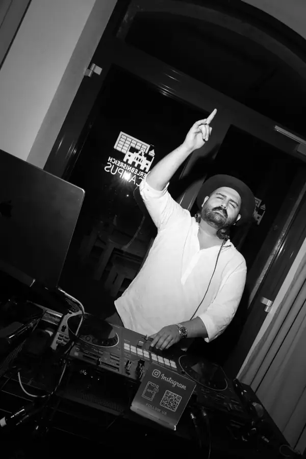 DJ SAM mit erhobener Hand am Pult &ndash; Schwarzwei&szlig;