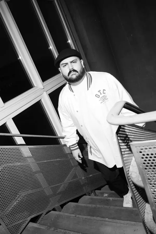 DJ SAM in Collegejacke auf Treppe &ndash; Schwarzwei&szlig;