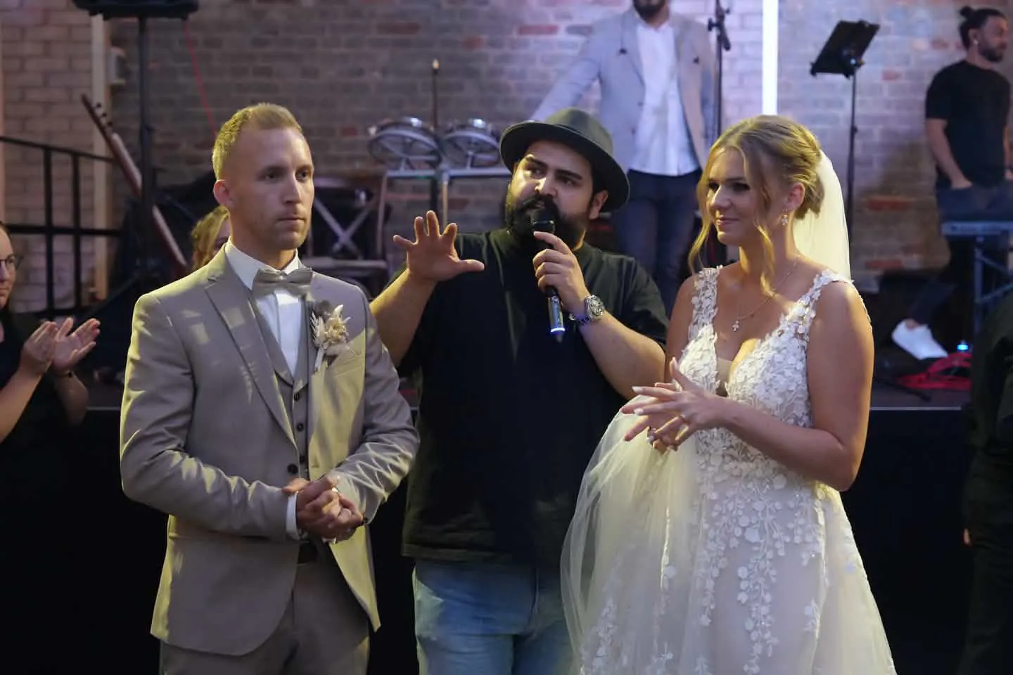 Der S&auml;nger der Live-Band mit Mikrofon zwischen Braut und Br&auml;utigam im Platin