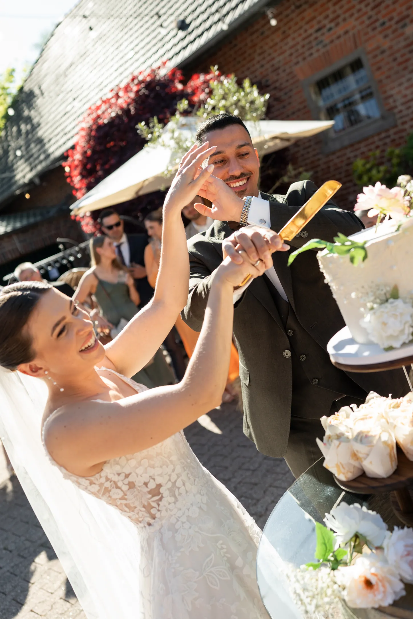 Brautpaar schneidet lachend die Hochzeitstorte im Innenhof des Scheunentraums in Aachen an