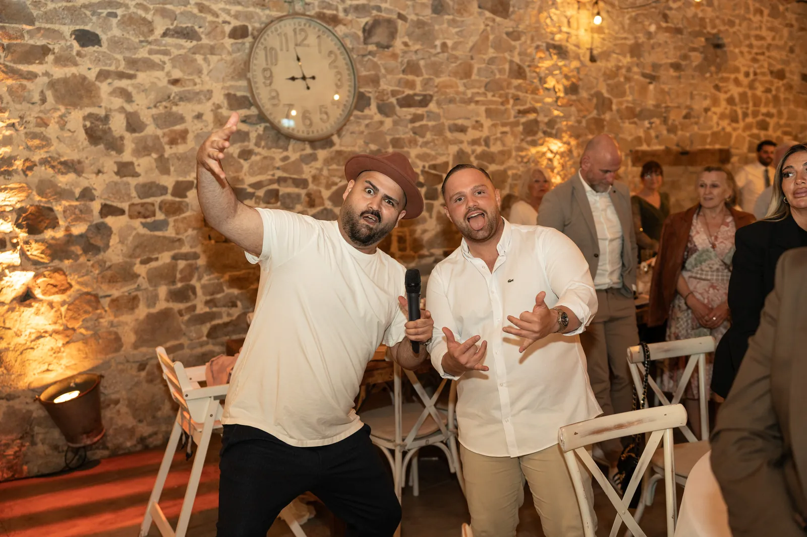 DJ SAM am Mikrofon, während die Braut vor der Natursteinwand des Scheunentraums strahlt und die Gesellschaft jubelt