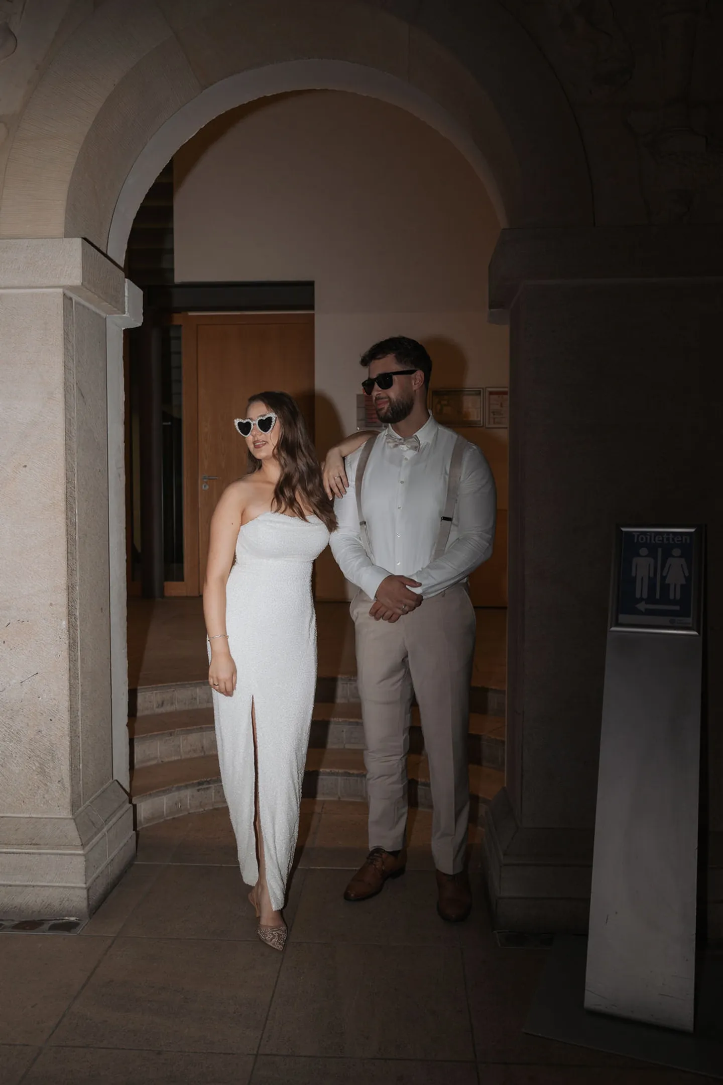 Brautpaar S. und M. im Torbogen von Schloss Horst, beide mit Sonnenbrille
