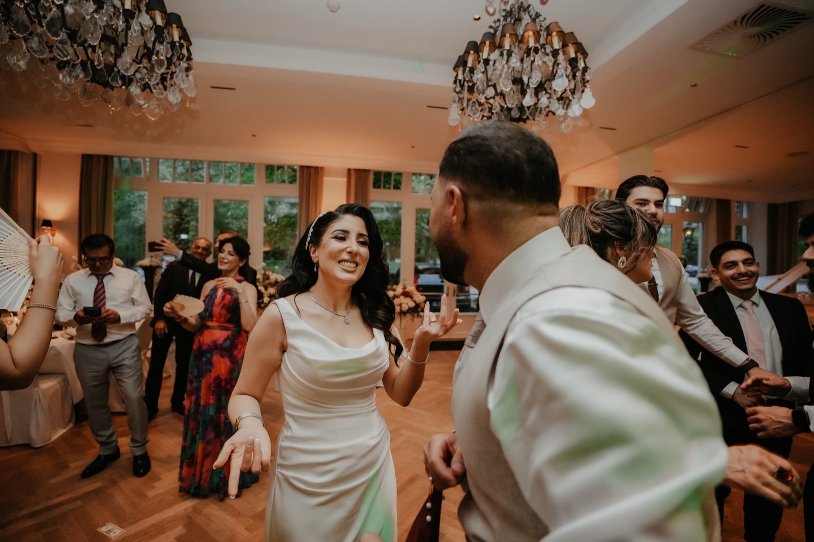 Strahlende Braut im Satinkleid tanzt mit dem Bräutigam auf ihrer türkisch-iranischen Hochzeit auf Gut Altona
