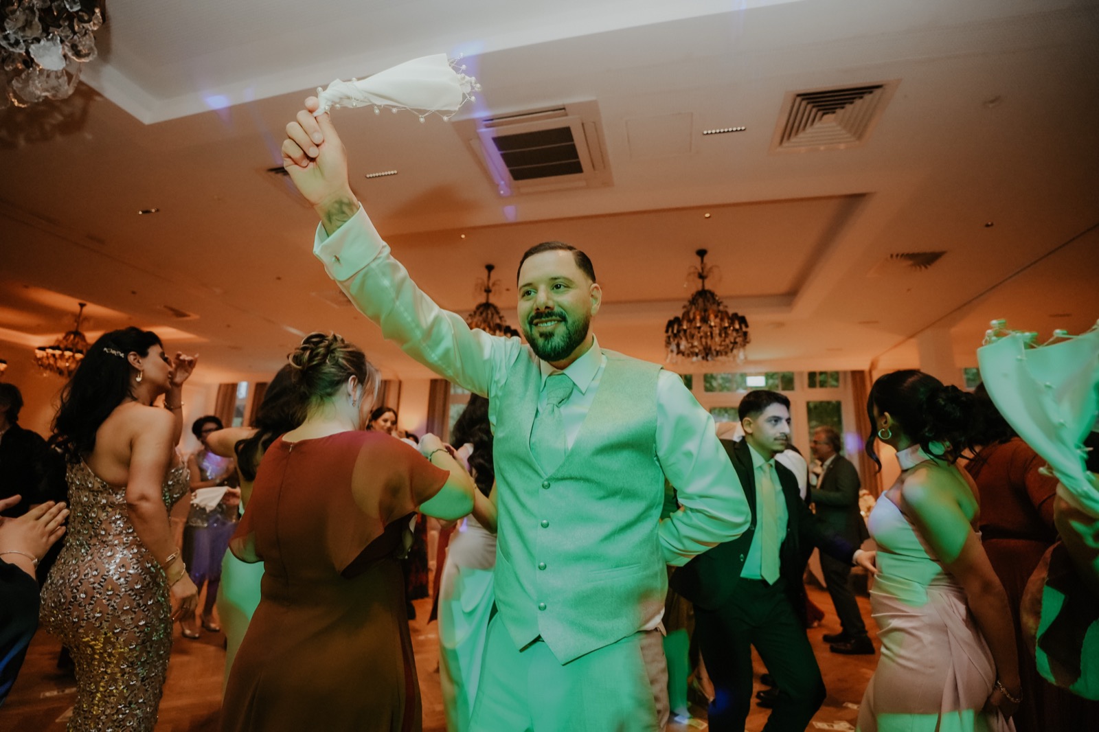 Bräutigam schwenkt lachend ein Tuch beim traditionellen Tanz auf der türkisch-iranischen Hochzeit auf Gut Altona